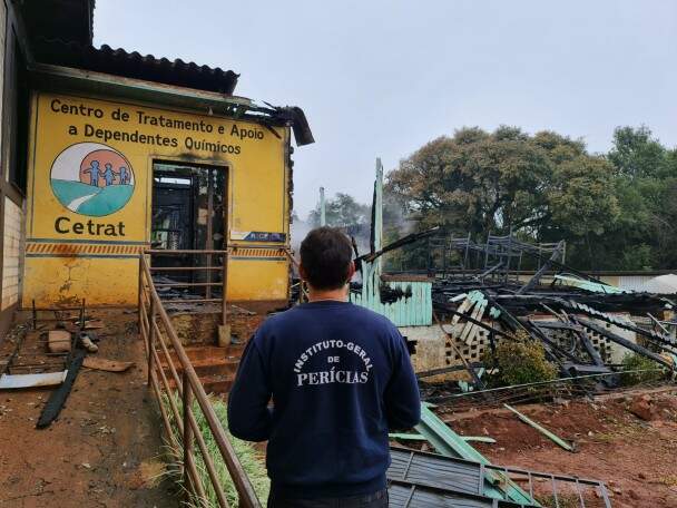 Homem com moletom da perícia em frente a prédio amarelo onde se lê Cetrat